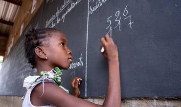 Una niña escribe en una pizarra en un espacio de aprendizaje temporal en Burkina Faso.