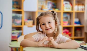 Una niña en edad preescolar está sentada en el pupitre de un aula de un centro de apoyo a la educación infantil en Ucrania